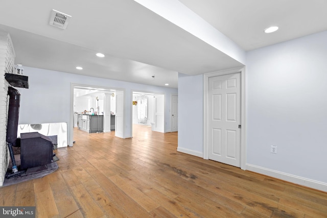 interior space with hardwood / wood-style flooring, a wood stove, and sink