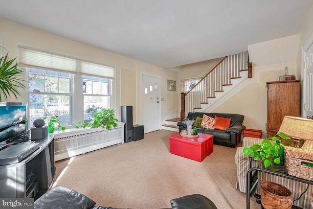 living area with stairs, radiator heating unit, and carpet