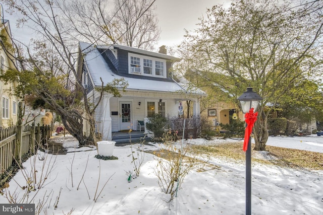 view of front of house with covered porch, a chimney, and fence