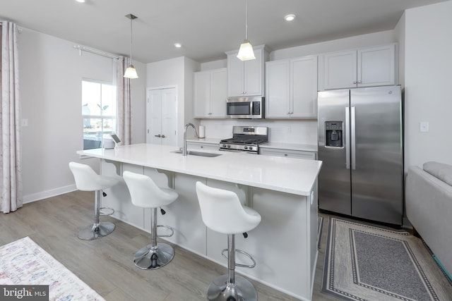 kitchen with pendant lighting, tasteful backsplash, sink, a kitchen island with sink, and stainless steel appliances