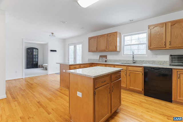 kitchen featuring black dishwasher, sink, a center island, light stone countertops, and light hardwood / wood-style flooring