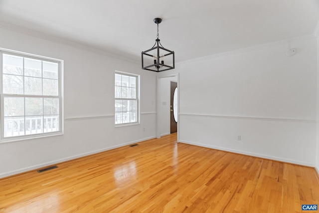 unfurnished room featuring crown molding, a notable chandelier, and light wood-type flooring