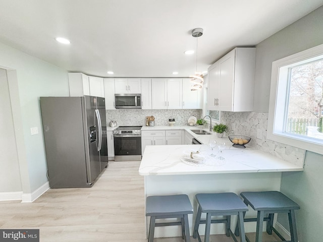 kitchen with stainless steel appliances, kitchen peninsula, sink, and white cabinets