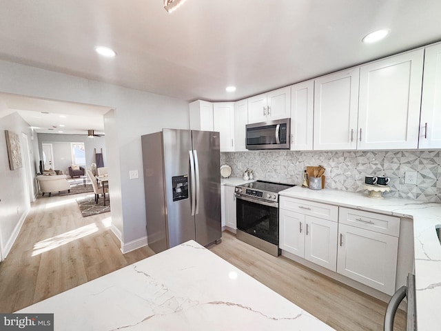 kitchen with appliances with stainless steel finishes, light stone countertops, and white cabinets