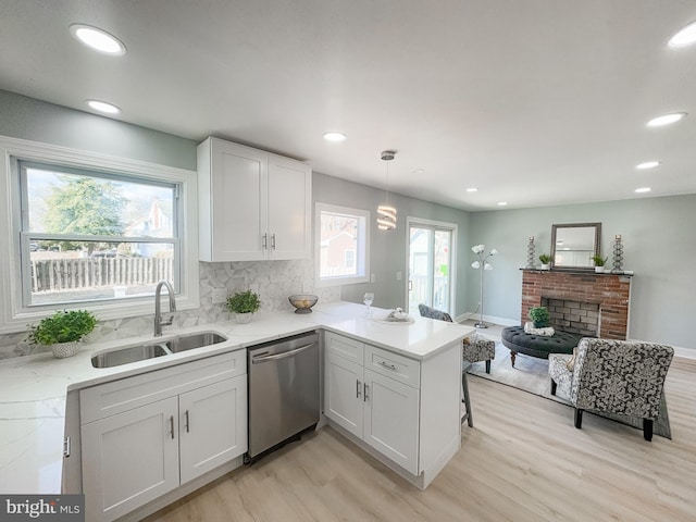 kitchen featuring dishwasher, sink, pendant lighting, and white cabinets