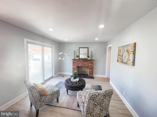 living room with a brick fireplace and light hardwood / wood-style floors