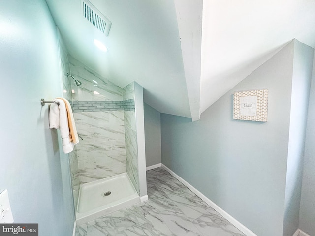 bathroom featuring a tile shower and vaulted ceiling