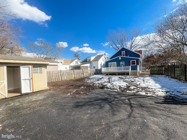 snow covered rear of property featuring a wooden deck and a shed