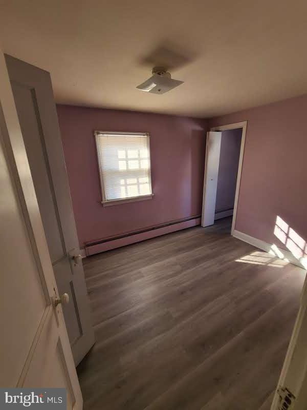 empty room with a baseboard radiator and dark hardwood / wood-style flooring