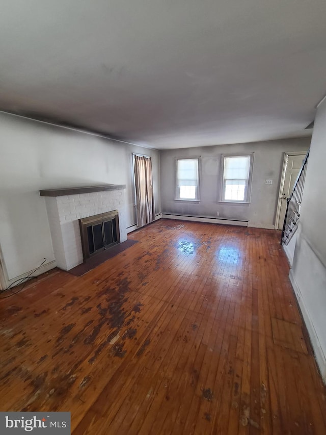 unfurnished living room featuring dark hardwood / wood-style flooring, a brick fireplace, and a baseboard radiator