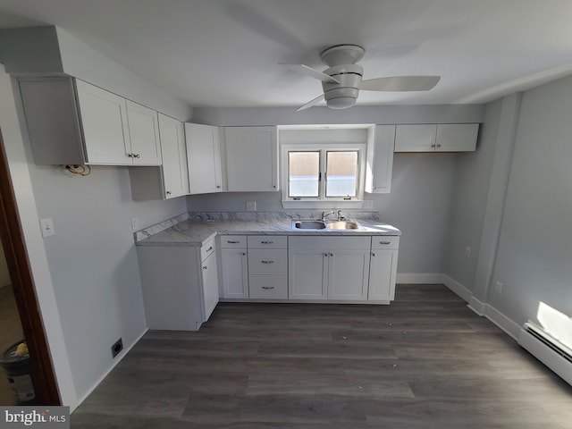 kitchen with sink, ceiling fan, a baseboard heating unit, dark hardwood / wood-style floors, and white cabinets