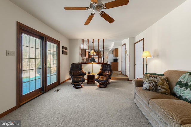 carpeted living room with visible vents, baseboards, and a ceiling fan