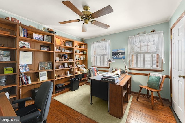 office area featuring baseboards, crown molding, a ceiling fan, and hardwood / wood-style flooring