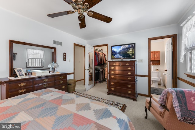 bedroom featuring visible vents, ensuite bath, a closet, light carpet, and a walk in closet