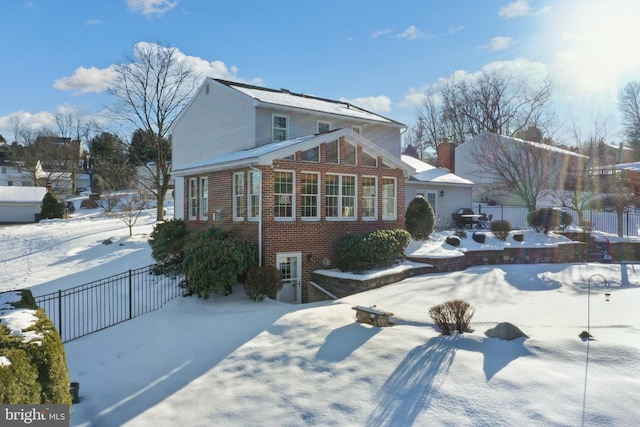 view of front facade featuring brick siding and fence