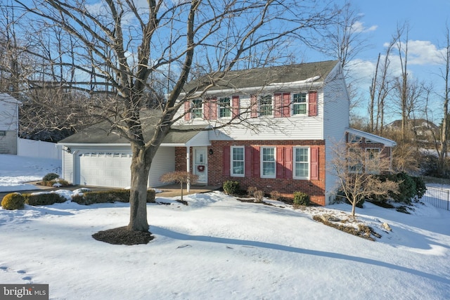 colonial house featuring brick siding, a garage, and fence