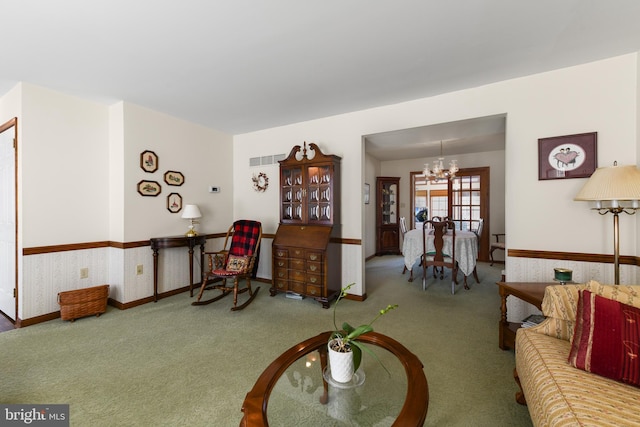 living room with a chandelier, visible vents, wallpapered walls, and carpet