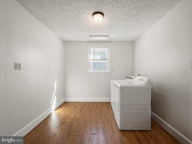 washroom featuring baseboards, laundry area, wood finished floors, and washer and dryer