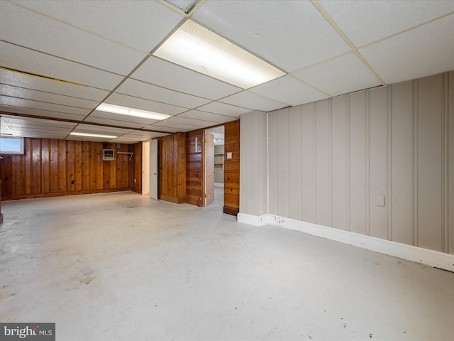 finished below grade area featuring a paneled ceiling and wood walls