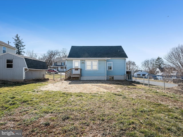 back of property featuring an outbuilding, a yard, roof with shingles, and fence