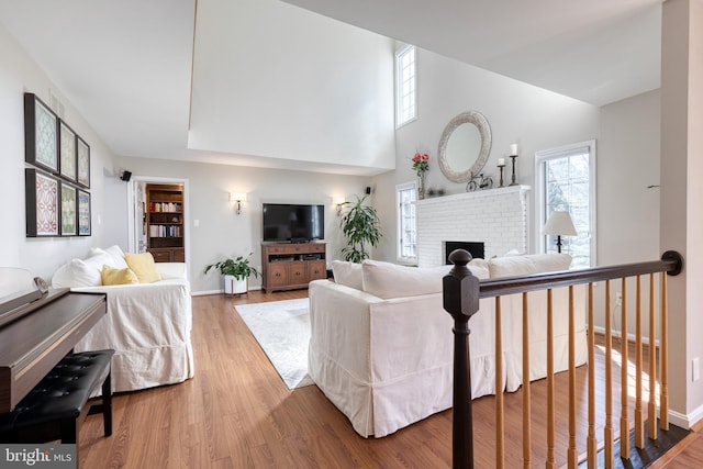 living area with a brick fireplace, baseboards, and wood finished floors