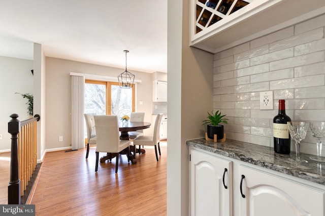 dining space featuring a notable chandelier, light wood-style flooring, and baseboards