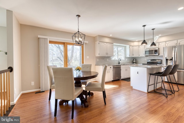 dining space with a chandelier, recessed lighting, light wood-type flooring, and baseboards