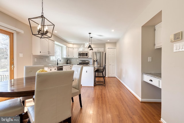 dining room with baseboards, recessed lighting, a chandelier, and light wood-style floors