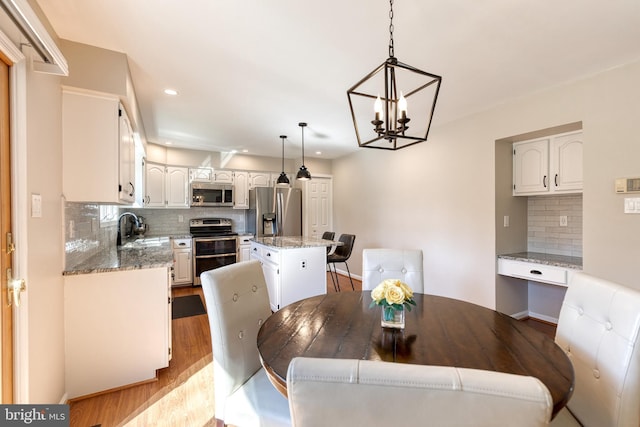 dining area featuring light wood-style floors, baseboards, an inviting chandelier, and recessed lighting