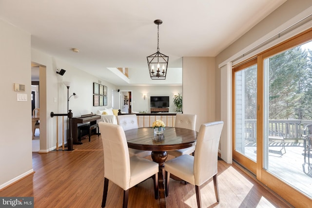 dining room with a notable chandelier, baseboards, and light wood-style floors