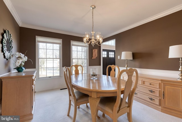 dining room with light carpet, a notable chandelier, visible vents, and crown molding