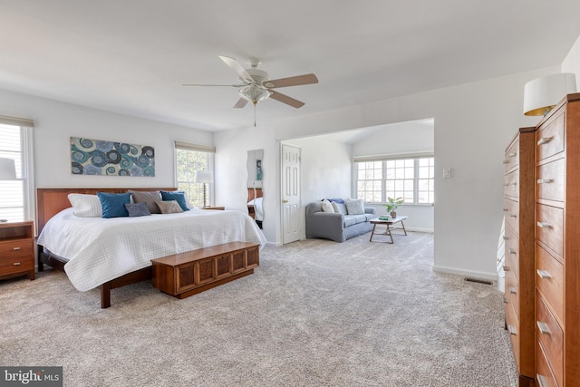 carpeted bedroom with baseboards, multiple windows, visible vents, and a ceiling fan