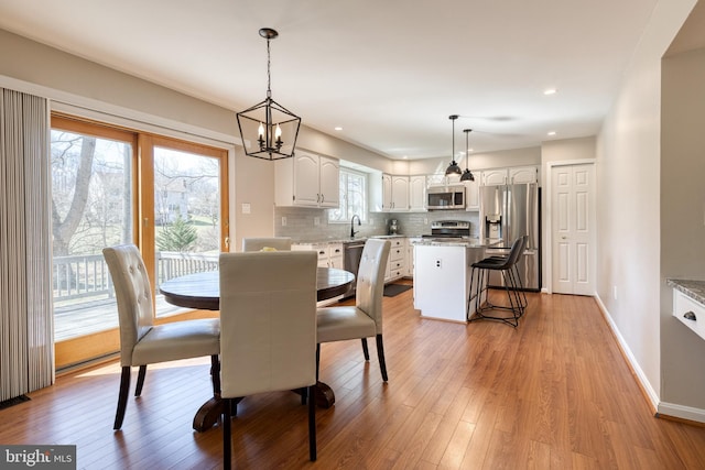 dining room with recessed lighting, light wood-type flooring, and baseboards