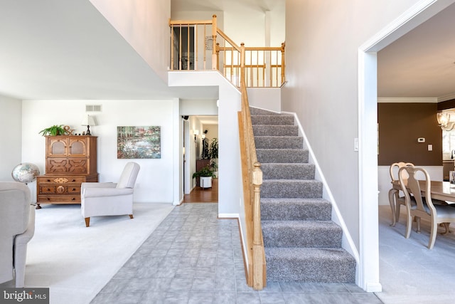 stairway featuring visible vents, a towering ceiling, carpet flooring, a chandelier, and baseboards