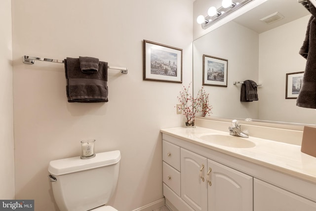 half bath featuring visible vents, vanity, and toilet