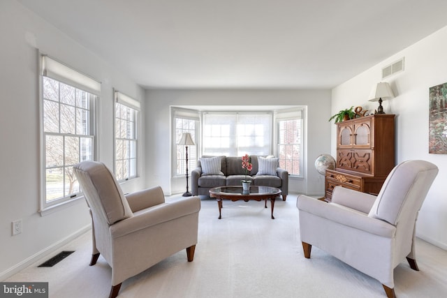 living area featuring a healthy amount of sunlight, visible vents, and light carpet