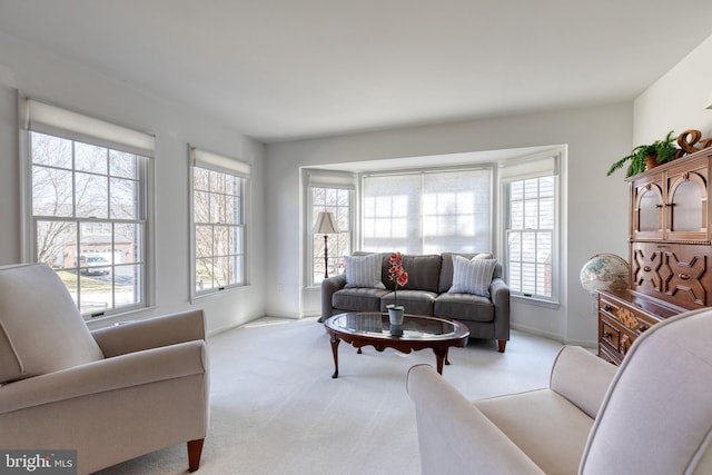 living area featuring light carpet and baseboards