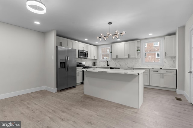 kitchen with appliances with stainless steel finishes, decorative light fixtures, a center island, and white cabinets