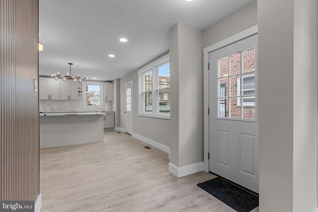 interior space with a notable chandelier, a wealth of natural light, and light wood-type flooring