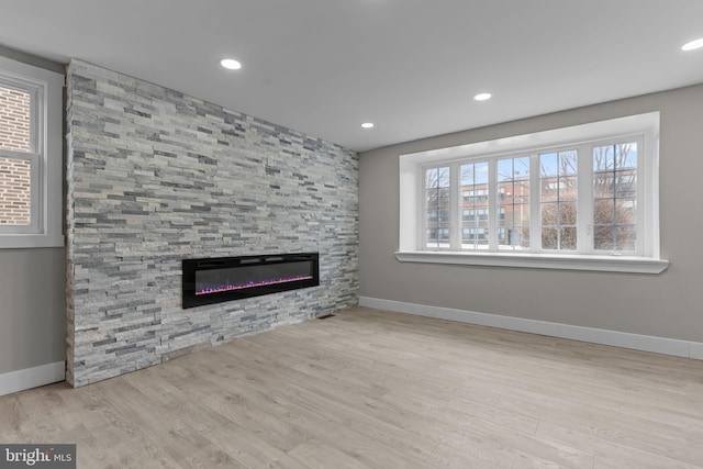 unfurnished living room featuring a wealth of natural light, a fireplace, and light wood-type flooring