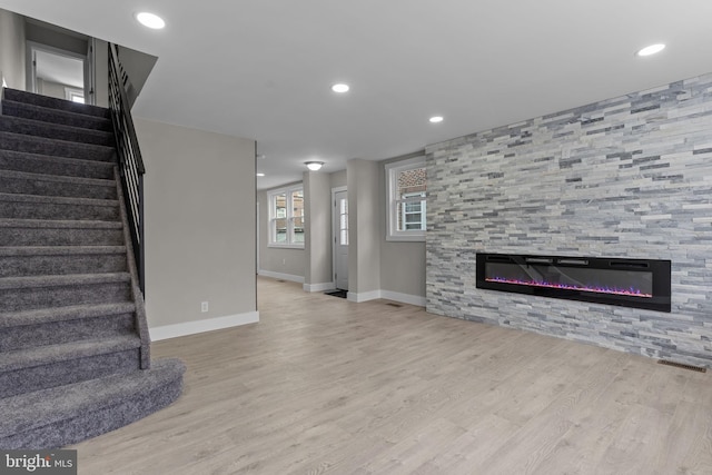 unfurnished living room featuring light hardwood / wood-style flooring and a tile fireplace