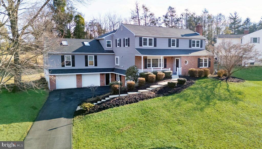 front of property with a garage, covered porch, and a front yard