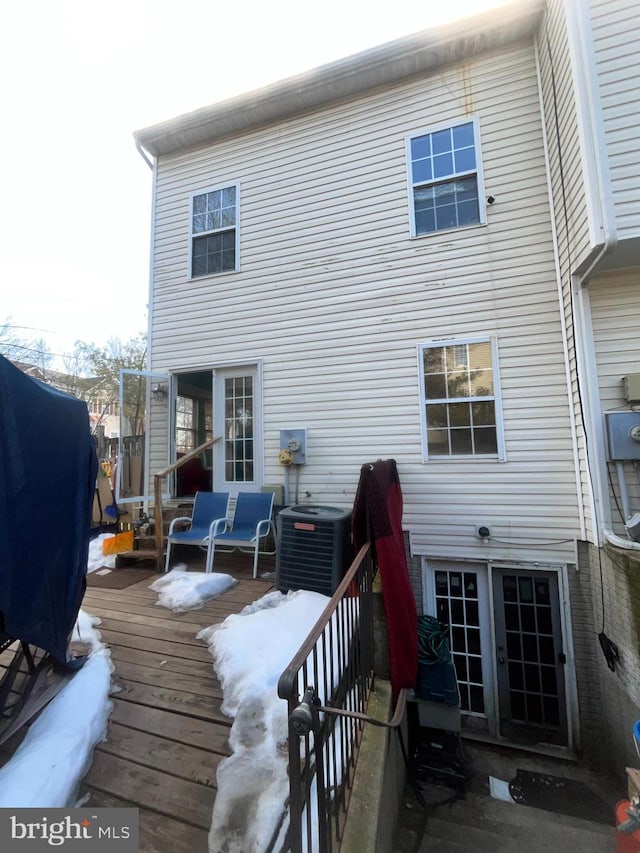 snow covered back of property with a wooden deck and central air condition unit