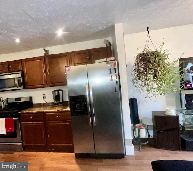 kitchen featuring stainless steel appliances, a textured ceiling, and light wood-type flooring