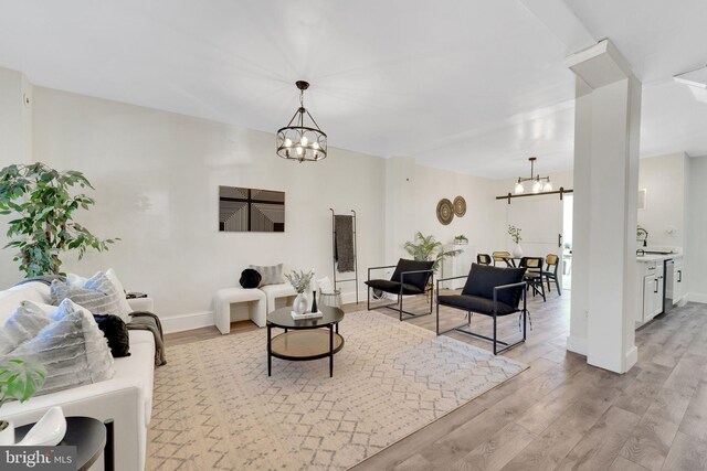 living area featuring baseboards, light wood finished floors, and a chandelier