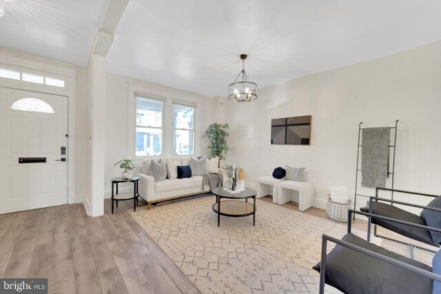 living room with baseboards, a notable chandelier, and light wood-style flooring