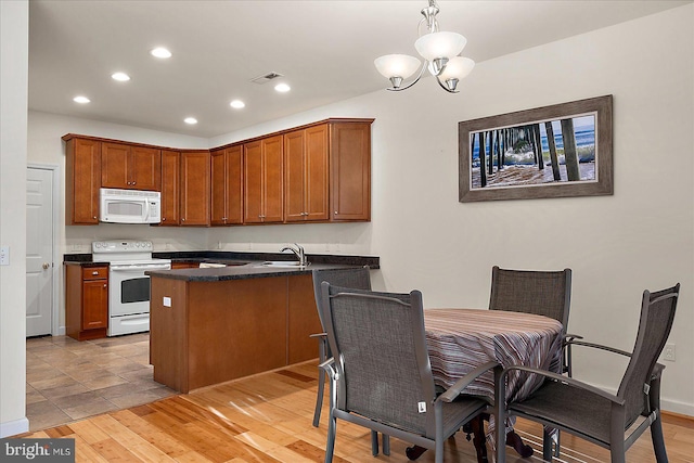 kitchen featuring hanging light fixtures, light wood-type flooring, white appliances, and kitchen peninsula