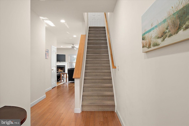 stairway with hardwood / wood-style flooring and ceiling fan