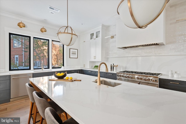 kitchen featuring pendant lighting, sink, appliances with stainless steel finishes, light stone countertops, and white cabinets