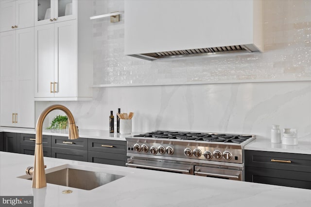 kitchen featuring premium range hood, sink, tasteful backsplash, range with two ovens, and white cabinets